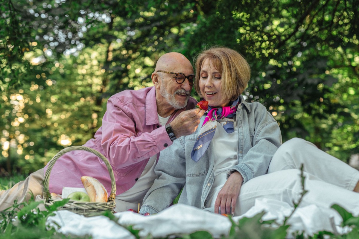 Une paire de personnes dans un jardin avec un panier à pique-nique