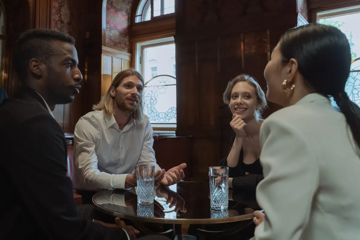 A diverse group of adults engaging in a friendly conversation in a warm, cozy restaurant setting.