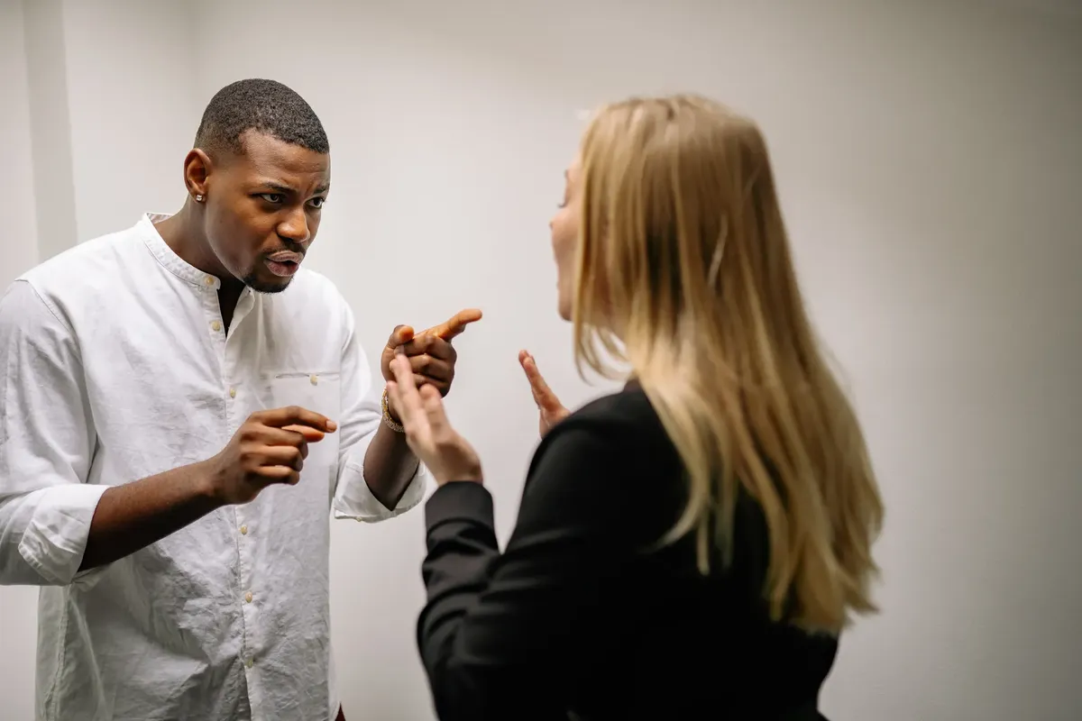 Two colleagues engaged in a heated discussion indoors, conveying intense emotions.