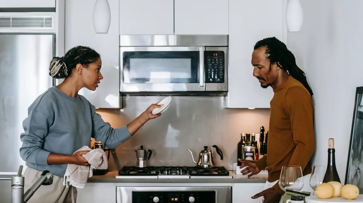 Side view of young black woman talking to dissatisfied male partner during conflict in house